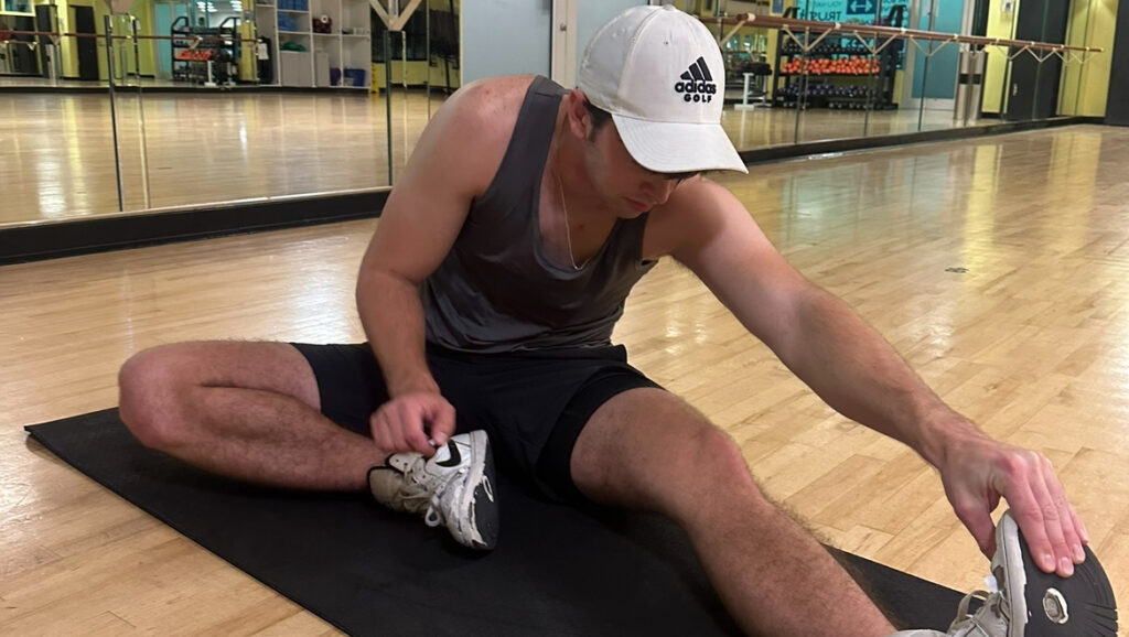 guy performing hamstring stretch for recovery, one of the best ways athletes build muscle