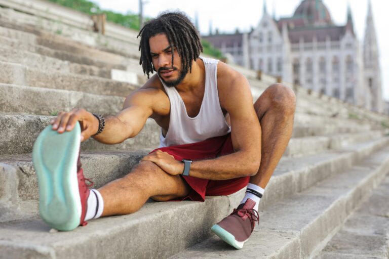 Guy performing a hamstring stretch to aid muscle recovery after a workout